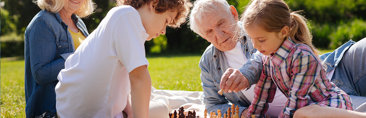 grandparents and children playing chess outdoor; image used for HSBC New Zealand Terms, Conditions, and Standard Contracts page
